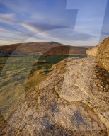 First sunlight on granite at the summit of Saddle Tor looking at Rippon Tor, Dartmoor National Park, Bovey Tracey, Devon UK