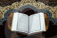 An open Holy Quran on wood stand.