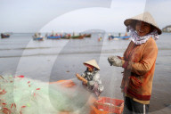 Fishermen repairing fishing nets at Tam Duong beach. Vung Tau. Vietnam.