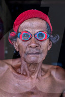 Portrait of a Bajau fisherman crafting wooden goggles from mangrove wood, Togian Island, Indonesia.