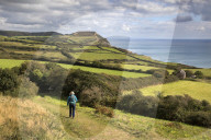 Walker along the SW Coast Path near Stonebarrow with Golden Cap in distance, Charmouth, Dorset, England, United Kingdom, Europe