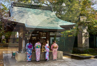 Japanese women in kimonos washing hands before entering the Tenmangu Shrine in Kyoto.