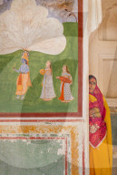 Portrait Hindu women standing next to art work inside Amer Fort, Jaipur.