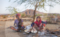 Portrait of young Hindu girl cooking and father playing an instrument, Pushkar.