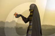 Ahir Woman in traditional colorful cloth pouring water at sunet, Great Rann of Kutch Desert, Gujarat, India