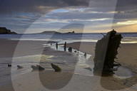 Sunset over the wreck of the Helvetia and Worms Head at Rhossili Bay, Gower, Wales, United Kingdom, Europe.