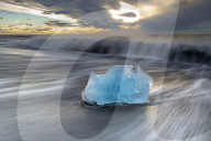 Glacier ice on Diamond Beach with crashing waves, near Jokulsarlon, South Iceland