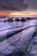 The Moeraki Boulders with dramatic sunrise at Moeraki Beach, Otago, New Zealand.