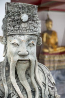 Detail of stone statue of guard and sitting Buddha in Wat Pho, Bangkok, Thailand.