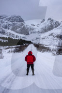 Male stood on snow covered road in arctic winter conditions with mountain back drop, Lofoten, Norway.