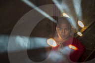 Novice monk praying with shafts of light, Bagan, Myanmar