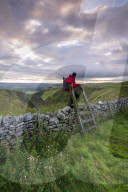 A walker climbing a stile at Winnats Pass, Winnats Pass, Hope Valley, Derbyshire