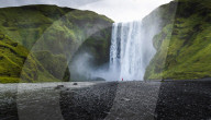 Visitor dwarfed by plunging waters of Skogafoss, Iceland‚Äôs most iconic waterfall, situated on the Skoga River, Southern Region.