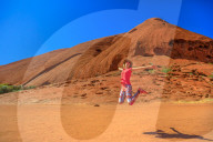 Tourist woman jumping at Ayers Rock in Uluru-Kata Tjuta National Park. Happy traveler enjoying along Lungkata walk connecting Kuniya walk to Mala carpark. Tourism in Northern Territory, Australia.