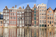 Dutch gables on a row of typical Amsterdam houses with reflections, Damrak canal, Amsterdam, Holland, Netherlands, EU, Europe