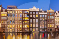 Dutch gables on row of typical Amsterdam houses at night with reflections Damrak canal, Amsterdam Holland Netherlands EU, Europe