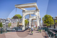 Cyclists riding across the Magere brug or Skinny bridge spanning the river Amstel in Amsterdam Netherlands Holland EU Europe