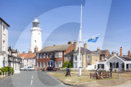 Southwold Lighthouse and houses with People sat on a bench St James Green East Cliff Southwold Suffolk England UK GB Europe