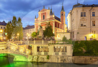 The Pink Franciscan Church and the triple bridge Tromostovje over the Ljubljanica river at night Ljubljana Slovenia EU Europe