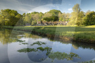 Arlington Row cottages across the River Coln in the Cotswolds village of Bibury, Gloucestershire, England. Spring (May) 2019.