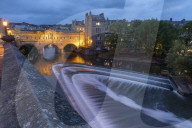 Pulteney Bridge and weir on the River Avon at dusk, Bath, Somerset, England. Summer (June) 2019.