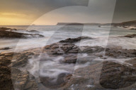 Waves swirl over rocky ledges at sunset on the North Cornwall coast, England. Summer (July) 2019.