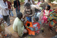 Mali tribeswoman holding hair of child having her head shaved by temple pundit at the festival of Shivraatri, Koraput, Odisha