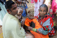Mali tribeswoman holding hair of child having had her head shaved for choula, at the festival of Shivraatri, Koraput, Odisha