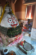 Musician plays the drum at the shrine to Lord Jagannath inside the village temple, rural Odisha