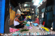 Two men in Malik Ghat flower market threading floral garlands, Kolkata, West Bengal