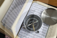 Quran and a Qibla compass to indicate the direction of Mecca. Close-Up.