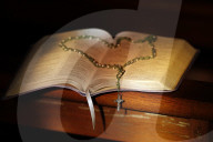Open bible and rosary in a church.