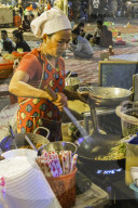 Chef frying noodles in a wok at Phsar Kandal night market near the riverfront; Phsar Kandal, city centre, Phnom Penh, Cambodia