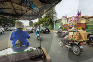 Passenger view from moving remork-moto (motorcycle & carriage), typical cheap transport here. City centre, Phnom Penh, Cambodia