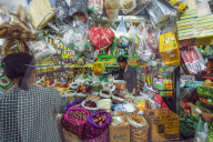 Woman & well-stocked stall selling goods & groceries at this huge old market; Central Market, city centre, Phnom Penh, Cambodia