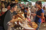 Girl wearing headphones buys food in the eating area of this huge old market; Central Market, city centre, Phnom Penh, Cambodia