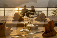 Restaurant tables set for dinner and couple overlooking lake at sunset, Como, Province of Como, Lake Como, Lombardy, Italy, Europe