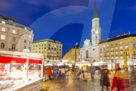 View of Christmas Markets stalls and St. Michael Catholic Church in Michaelerplatz at dusk, Vienna, Austria, Europe