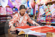 Woman using traditional weaving machine, Lijiang, Yunnan Province, China