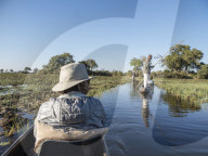 Tourists being poled through the shallow water by Mokoro in the Okavango Delta, Botswana.