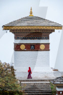 Single nun walking past temple at Dochula Pass, Bhutan.