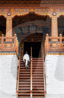 Bhutanese man in traditional dress climbing stairs into temple, Punakha Dzong.
