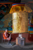 Portrait elderly Buddhist monk turning prayer wheel, Punakha Dzong.