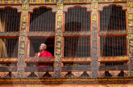 Portrait, mature Buddhist monk looking out of window, Punakha Dzong.