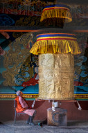 Portrait elderly Buddhist monk turning prayer wheel, Punakha Dzong.