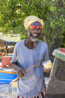 Grinning man repairs boat, white sand beach, colourful Saltwhistle Bay, Mayreau, Grenadines, St Vincent, West Indies, Caribbean