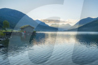 Man on water's edge admiring sunrise over the fjord, Jostedalsbreen National Park, Oppstryn, Sogn og Fjordane county, Norway