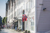 Tourists look at shops and traditional wood buildings in Bryggen old street, Bergen, Hordaland County, Norway