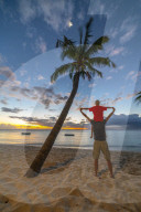 Rear view of cheerful father holding his son on neck standing on tropical sand beach, Le Morne Brabant, Indian Ocean, Mauritius