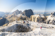 Hikers admiring Sella Pass, Sassolungo and Sassopiatto from top of Sass Pordoi, Dolomites, Trentino, Italy